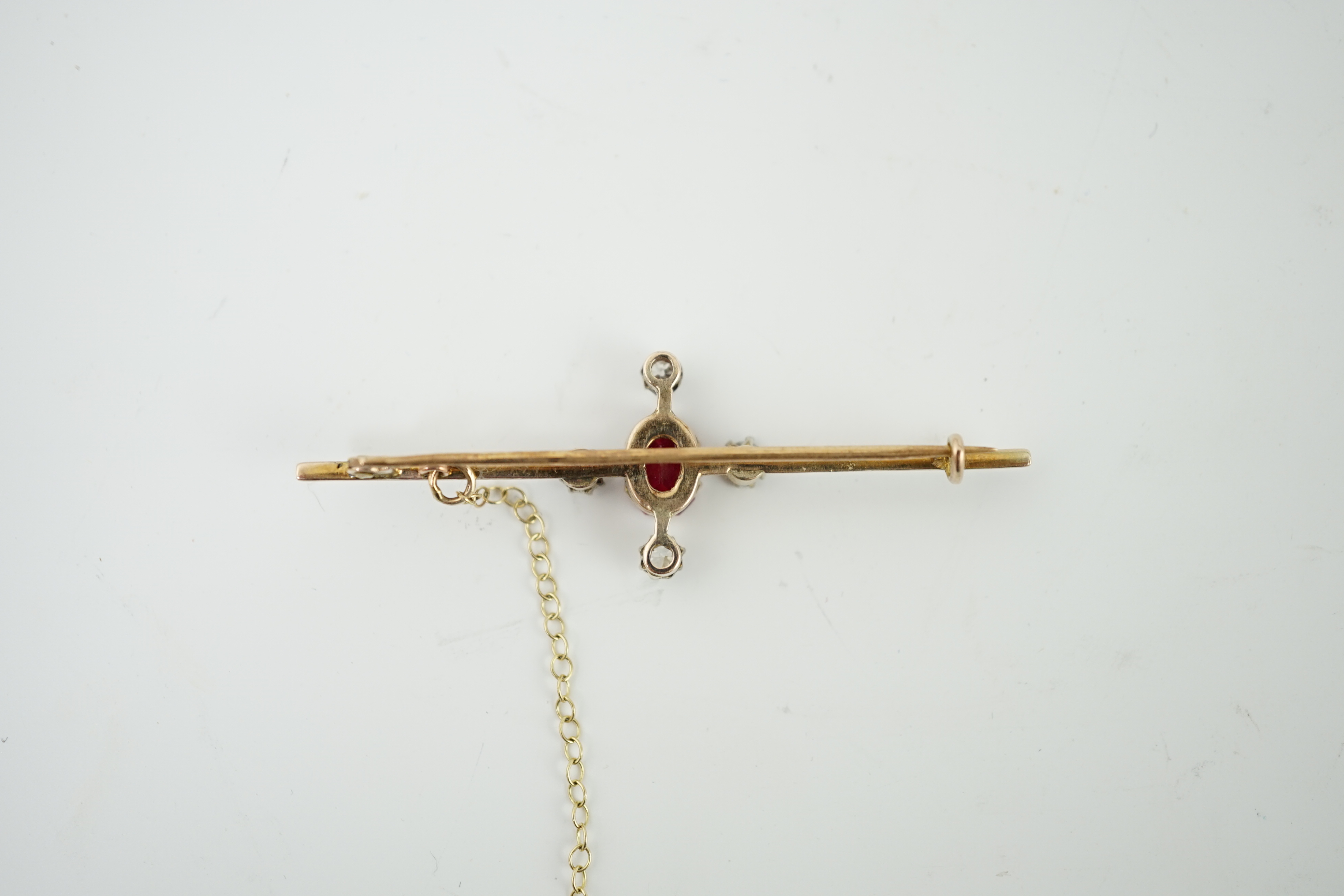 An early to mid 20th century gold, single stone oval cut synthetic ruby and four stone round cut diamond set bar brooch